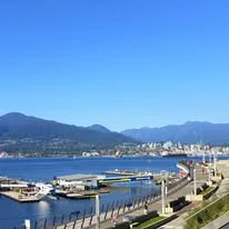 Boats docked at a waterfront marina, with the North Shore mountains rising across the harbour