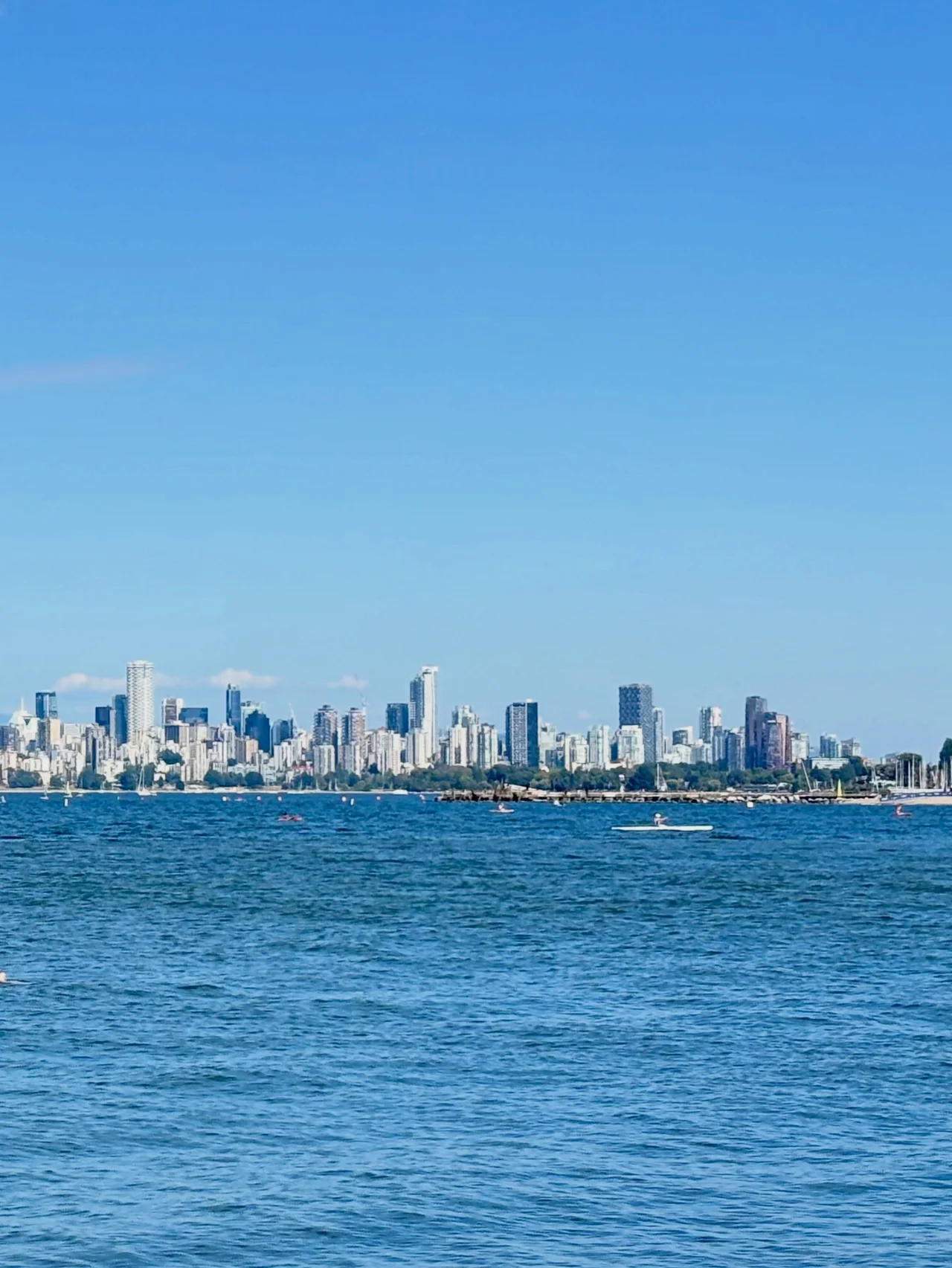 Downtown Vancouver's towers seen across calm, deep blue water under a clear sky