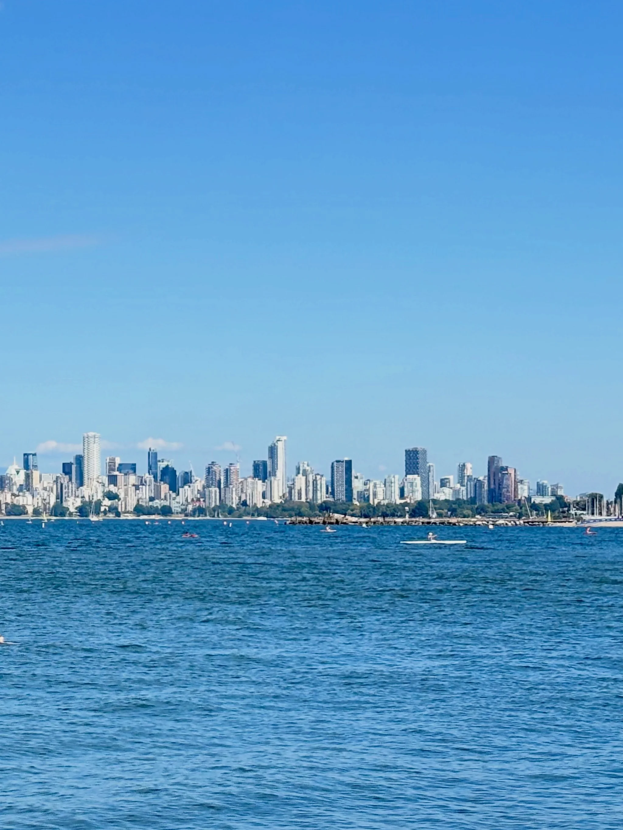 Downtown Vancouver's towers seen across calm, deep blue water under a clear sky